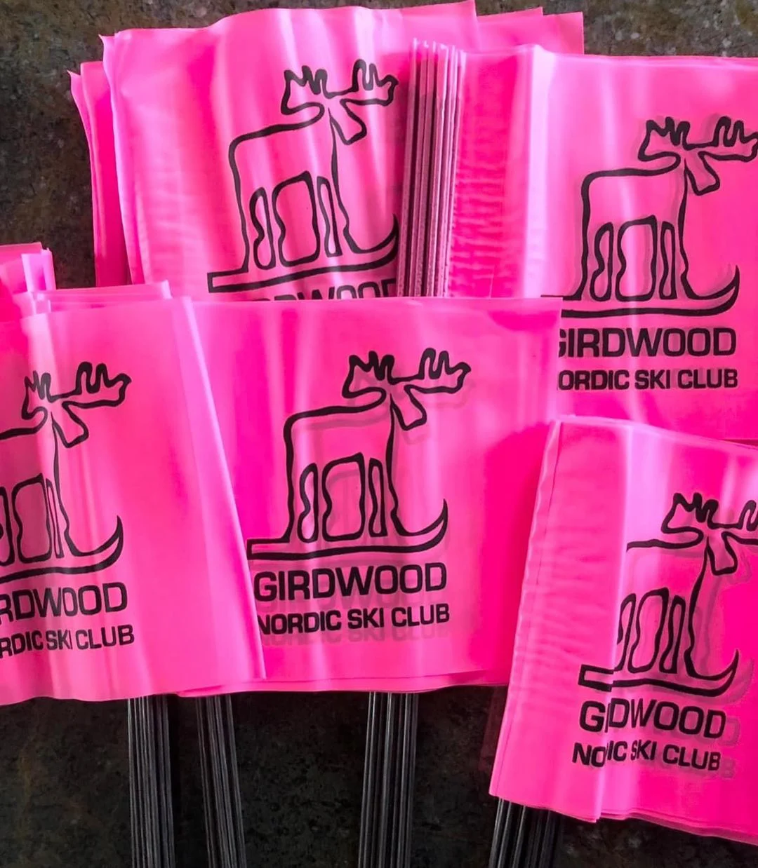 Bundles of pink marker flags on wire stakes, printed with the Girdwood Nordic Ski Club moose logo.